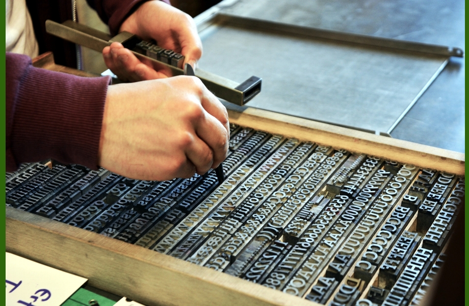 Die Arbeit in einer Druckerei - Foto Setzer nimmt Buchstaben aus einem Setzkasten und reiht sie zu Wörtern in einen Winkelhaken aneinander